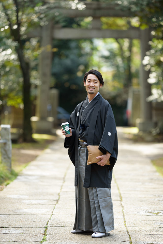 赤坂氷川神社の外でスタバのコーヒー片手に微笑む新郎